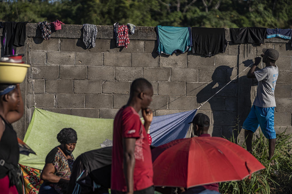 Mostly Haitian migrants wait on the side of a highway for buses provided by the INM.