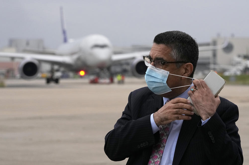 Ahmad Sarmast, founder and director of the Afghanistan National Institute of Music, puts on his face mask as an airplane arrives at Lisbon military airport bringing music students, faculty members and their families from Doha, on Dec. 13. 