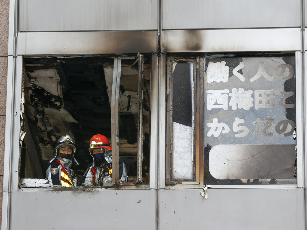 Firefighters stand on a floor at a building where a fire broke out Friday in Osaka, Japan, killing 24 people.