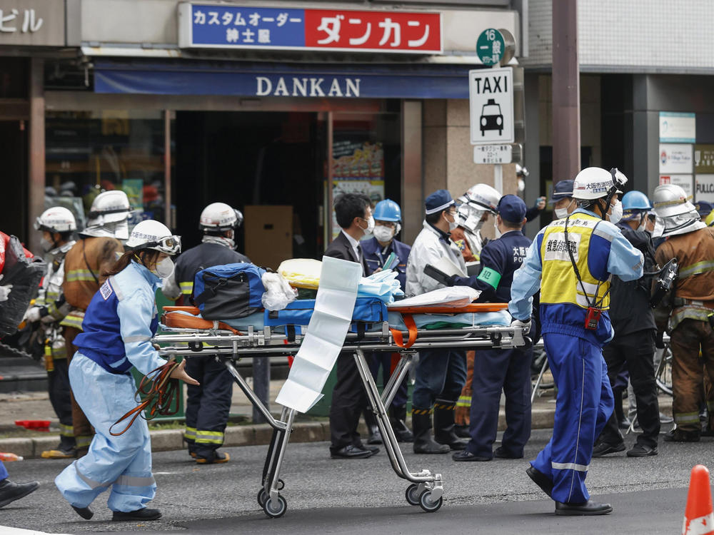 First responders carry a stretcher after a deadly fire at an eight-story building in a major business, shopping and entertainment district in Osaka on Friday.