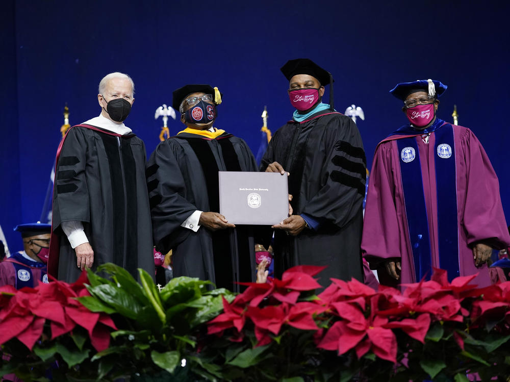 Rep. Jim Clyburn, D-S.C., second from left, holds his history degree with South Carolina State University Interim President Alexander Conyers, second from right, on stage with President Biden and Rodney Jenkins, chair of the Board of Trustees, right, during the South Carolina State University's 2021 Fall Commencement Ceremony in Orangeburg, S.C., on Friday.