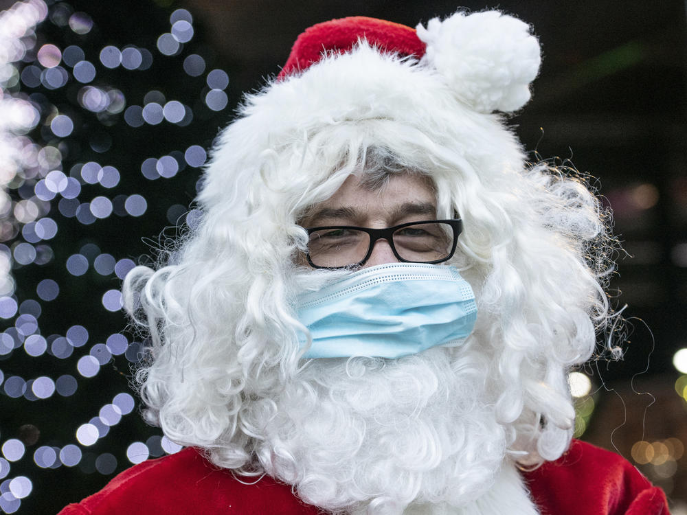 A Santa Claus in Germany wears a surgical mask in December 2020. If you're planning to take the kids to see Santa this year, experts say it's safest to keep everyone's masks on.