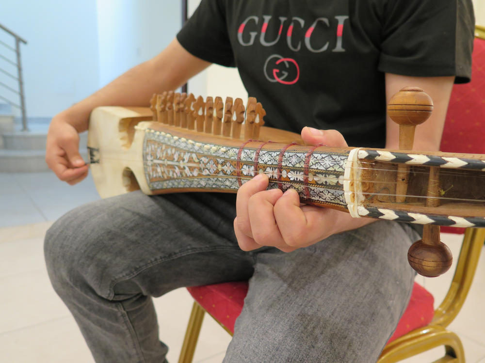 Fayaz, 19, holds his rubab. He is one of the lucky few who was able to take his own musical instrument with him when he fled Afghanistan.