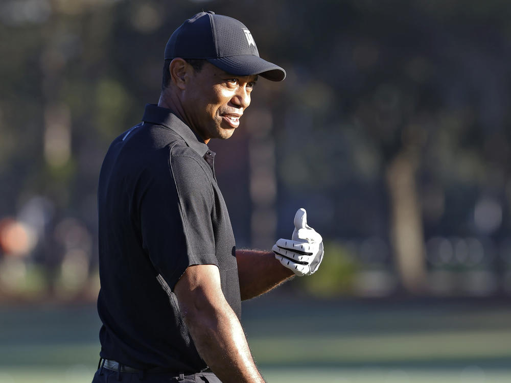 Tiger Woods smiles and gestures as he prepares to tee off during the first round of the PNC Championship golf tournament Friday in Orlando, Fla. Woods is back playing after getting injured in a car accident. He is paired with his son Charlie during the tournament.