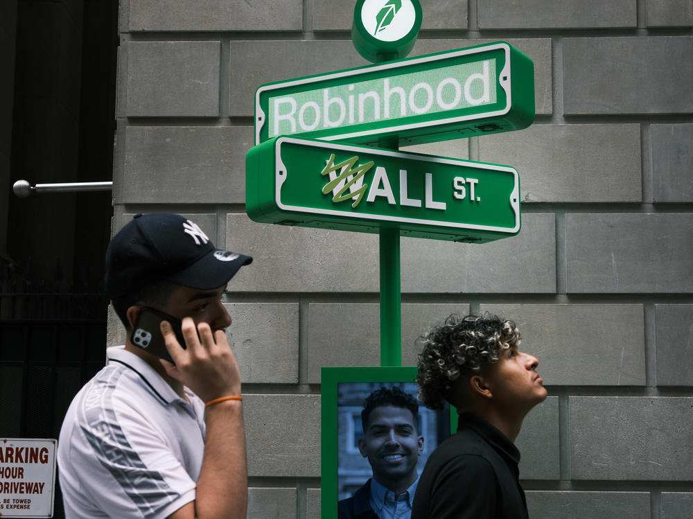 People wait in line for T-shirts at a pop-up kiosk for the online brokerage Robinhood along Wall Street in New York City on July 29, the day the company listed in stock markets. Millions of amateur investors are buying stocks through apps such as Robinhood.