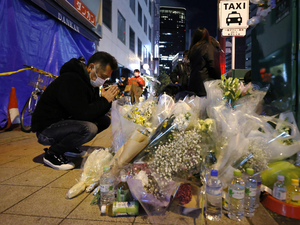 A mourner prays in front of offerings near a building where a fire broke out, in Osaka, western Japan on Saturday. Japanese police on Sunday identified a 61-year-old man as a prime arson suspect.