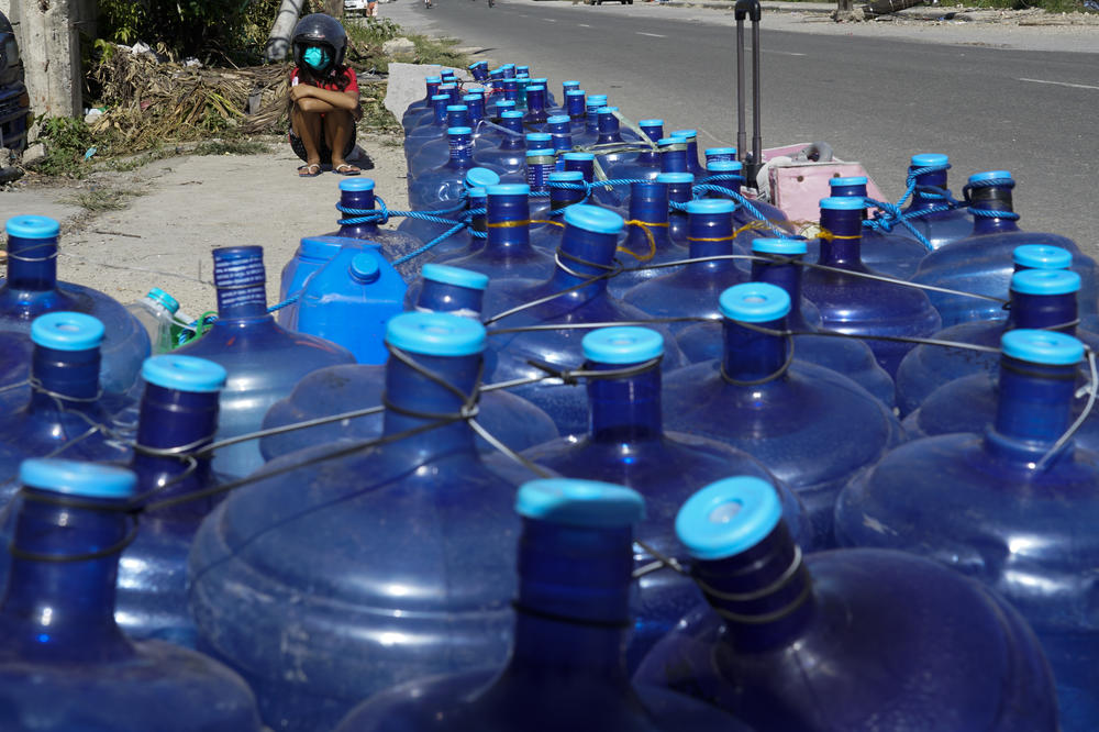 A boy sits beside water containers as residents line up for water as pipelines and electricity were damaged due to Typhoon Rai in Cebu province, central Philippines on Monday Dec. 20, 2021.