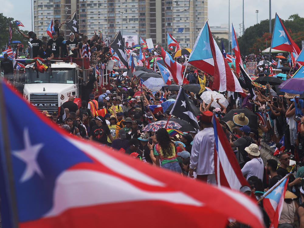 A truck carrying Bad Bunny, Ricky Martin and Residente joins with thousands of other people as they call on Puerto Rican Gov. Rosselló to step down.