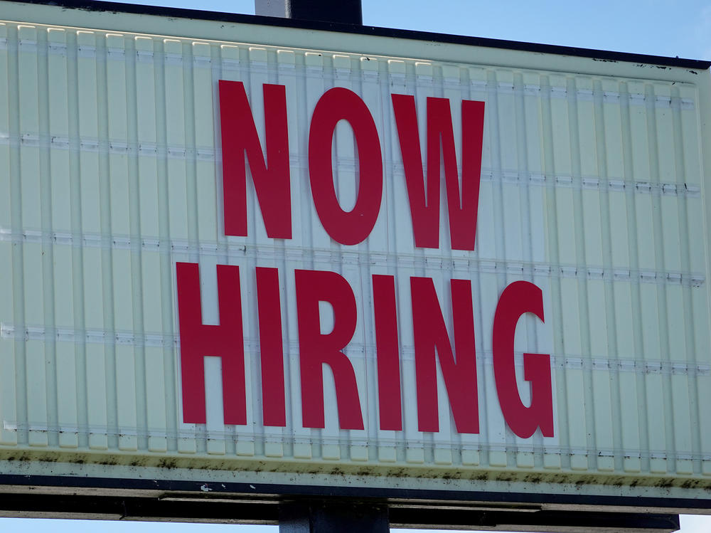 A 'Now Hiring' sign hangs in front of a Winn-Dixie grocery store in Miami on Dec. 3. Omicron is spreading at a time when some businesses such as restaurants are already strugging to find workers.