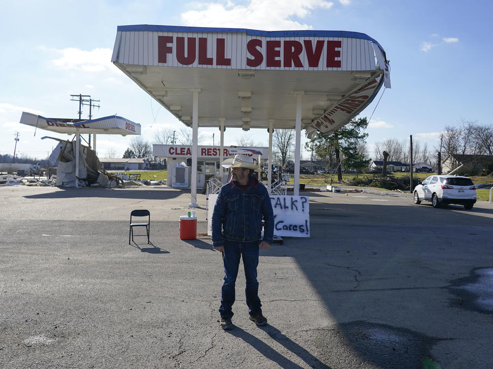 Dave 'Cowboy' Graham stands in front of a damaged gas station in Dawson Springs, Kentucky.