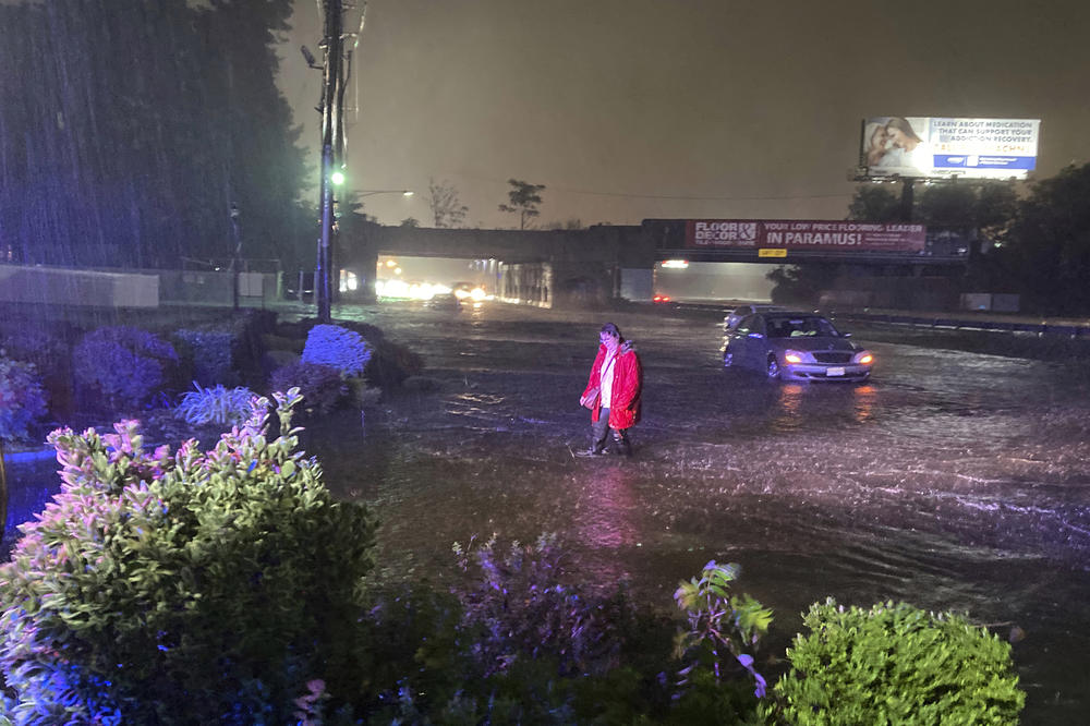 A woman walks away from her vehicle on the NJ-17 southbound roadway flooded by the remnants of Hurricane which <a href=