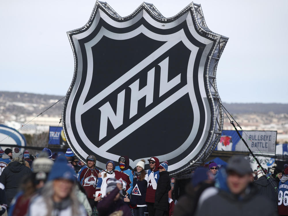 Fans pose below the NHL logo outside Falcon Stadium at the Air Force Academy in Colorado Springs, Colo., in February 2020.