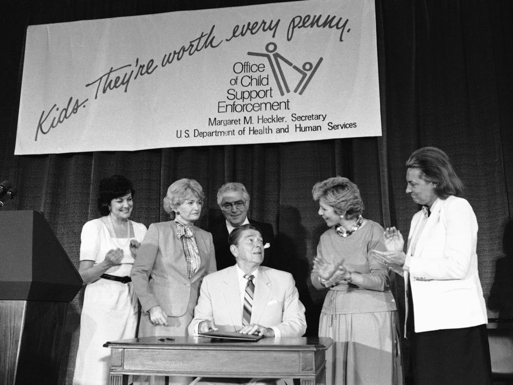 President Ronald Reagan signs legislation providing for the mandatory withholding of wages from parents delinquent in child support payments, as well as settling rules about foster care repayment, in 1984.