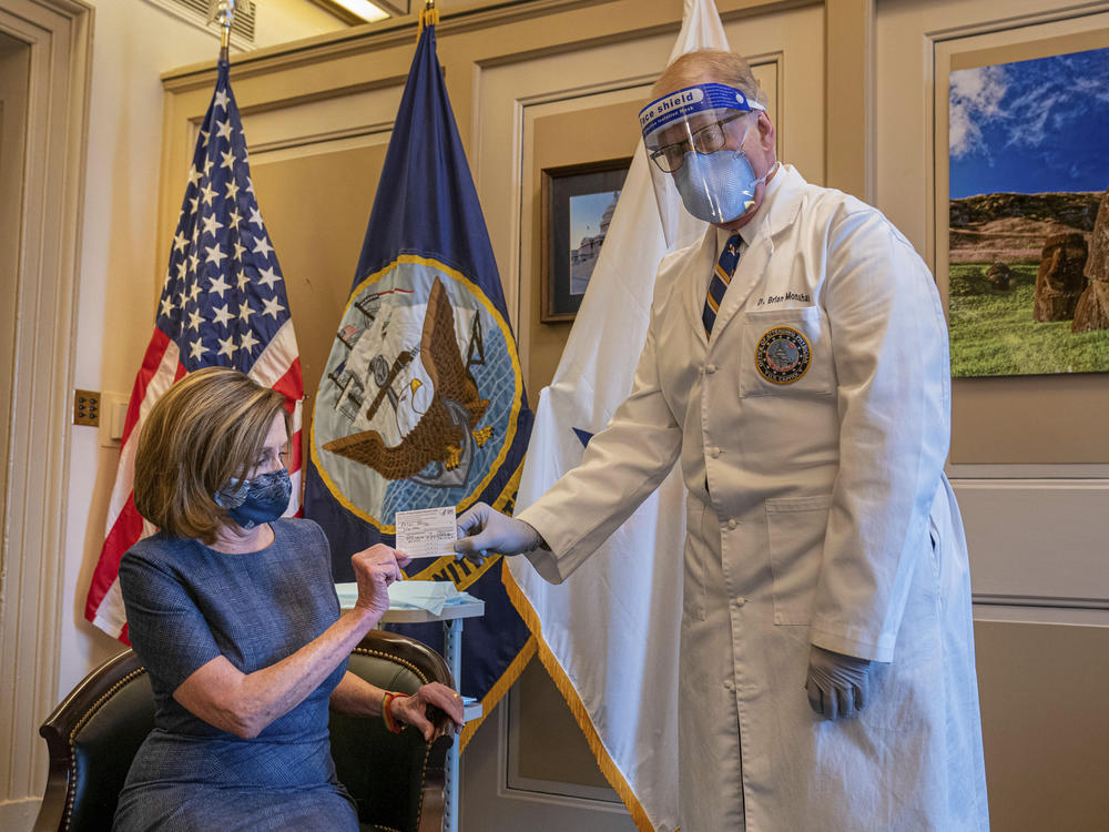 Speaker of the House Nancy Pelosi receives a COVID-19 vaccination record card from Dr. Brian Monahan, attending physician for the U.S. Congress, after getting a Pfizer-BioNTech COVID-19 vaccine on Dec. 18, 2020.