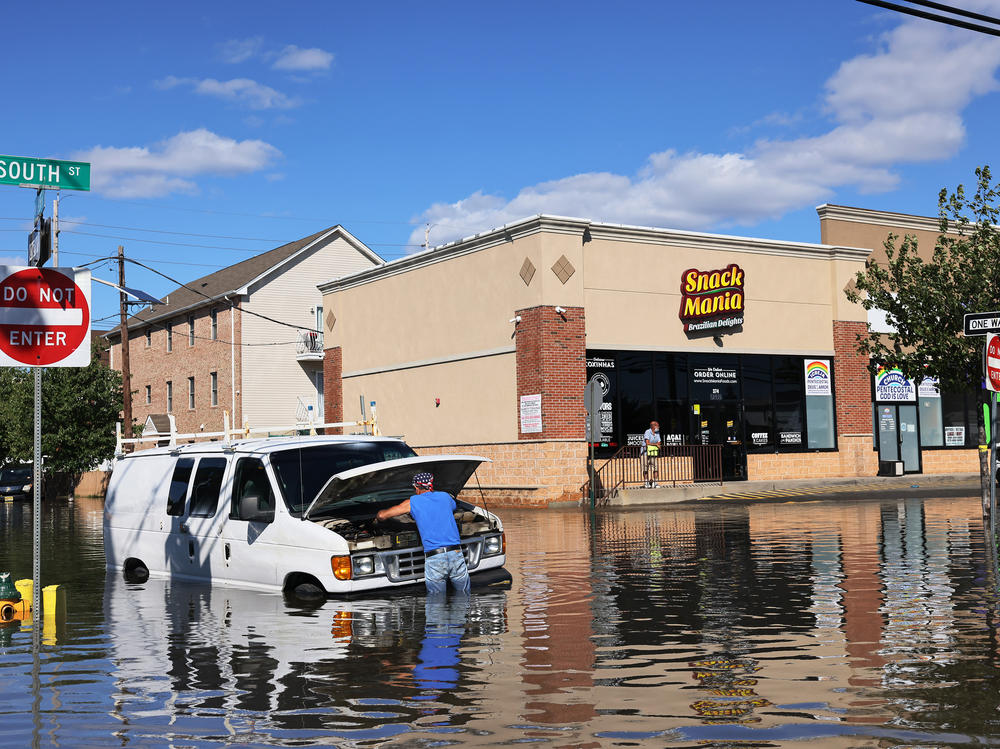 Abilio Viegas attempts to fix his flooded van on South Street in Newark, New Jersey after flooding cause by the remnants of Hurricane Ida.