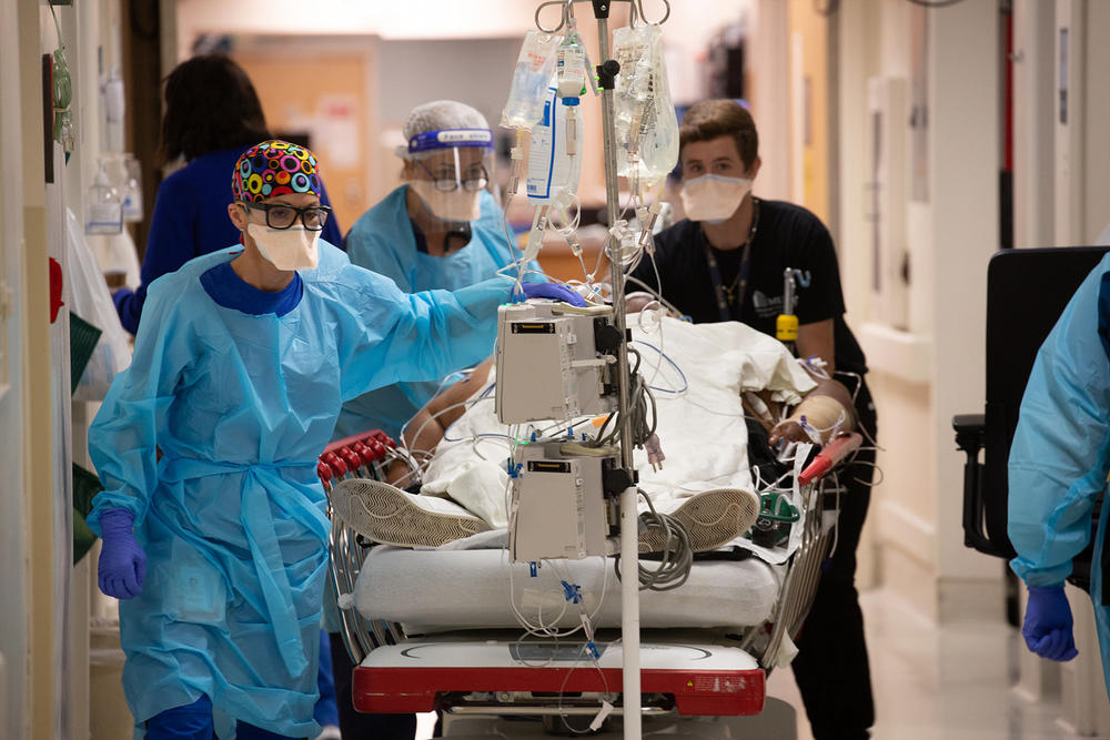Hospital staff roll a COVID patient into the intensive care unit at the Medical University of South Carolina after being intubated in the emergency room. The patient's wife was also hospitalized with COVID.