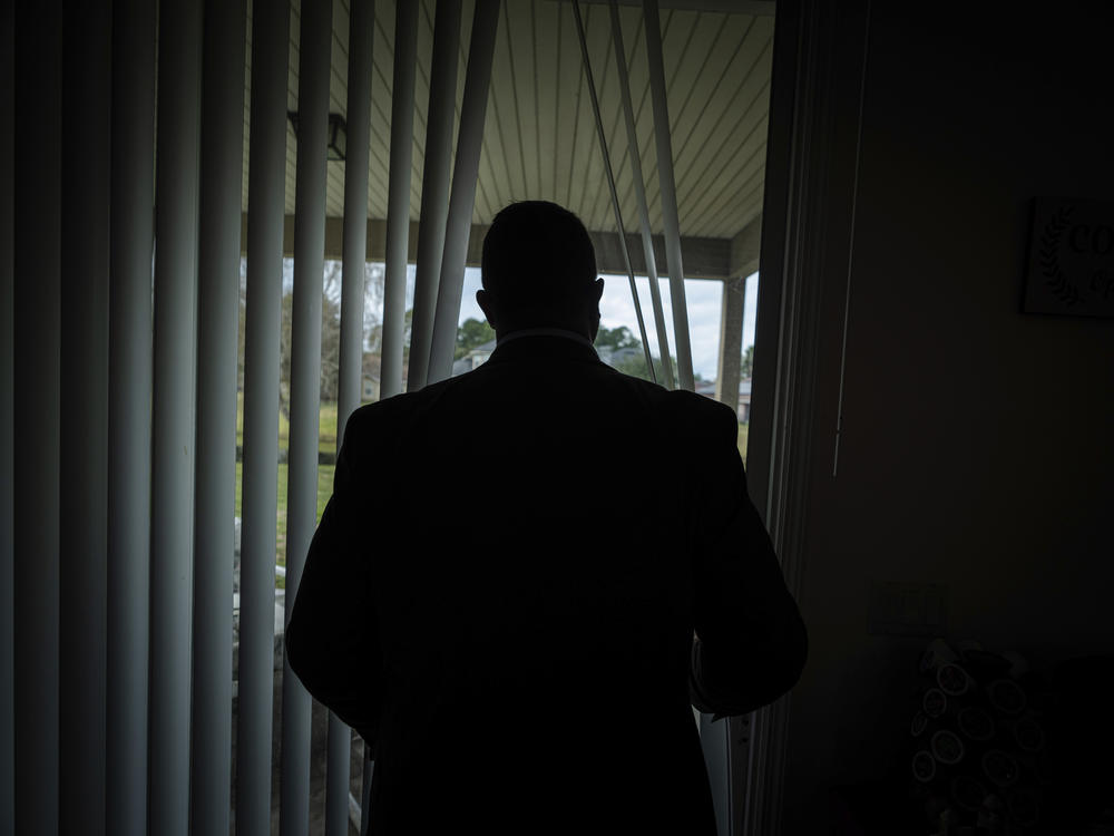 Joseph Moore looks out of a window at his home in Jacksonville, Fla. Today, he and his family live under new names.