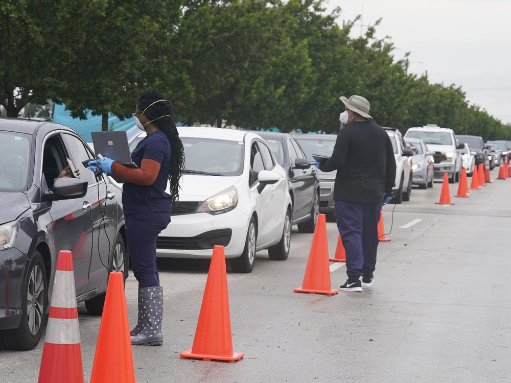 Employees of Nomi Health check in a long line of people seeking COVID-19 tests Tuesday in North Miami, Fla. The omicron variant has unleashed a fresh round of fear and uncertainty for travelers, shoppers and partygoers across the U.S.