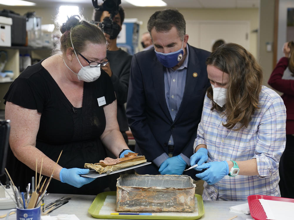 Virignia Gov. Ralph Northam ( center) watches as lead conservator for the Virginia Department of Historic Resources, Kate Ridgway (left) and Sue Donovon, conservator for Special Collections for the University of Virginia, remove the contents of a time capsule  from the pedestal that once held the statue of Confederate General Robert E. Lee.