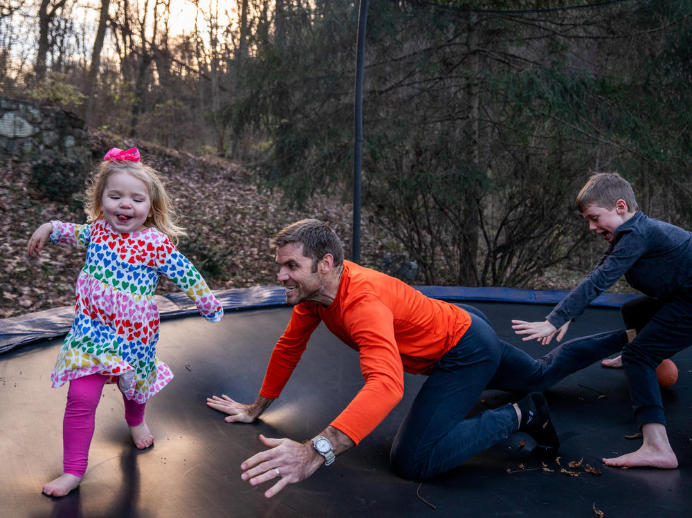 Blake Farmer plays with his kids, Louisa, 2, and Turner, 8, on the trampoline in their backyard in Nashville, Tennessee. After Thanksgiving, the family all had breakthrough COVID cases, resulting in a couple weeks spent at home. The trampoline served as a distraction for the kids, says Blake Farmer, their father.