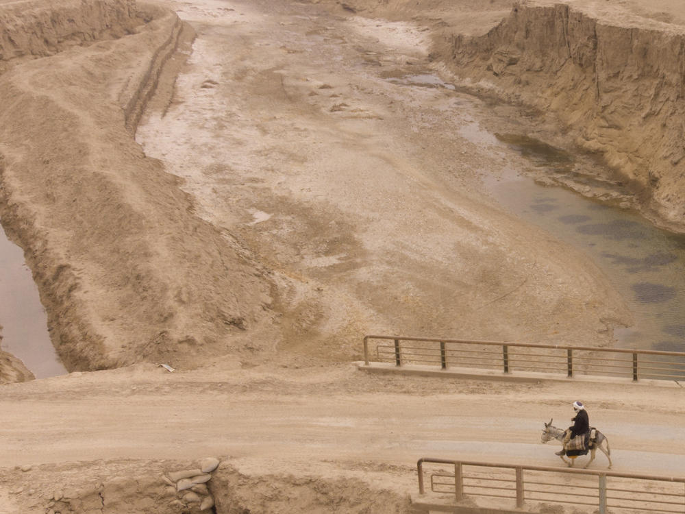 An Afghan farmer uses a donkey to carry water canisters across the dried-out river near Sang-e-Atash, Afghanistan. A severe drought has dramatically worsened the already desperate situation in the country.