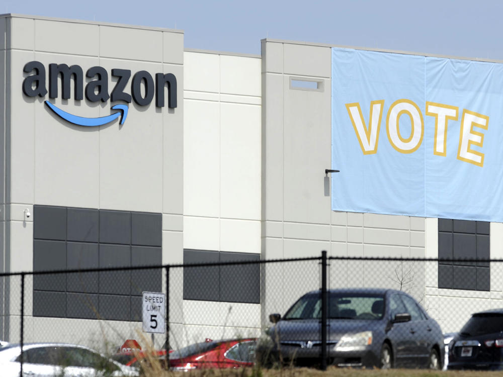 A banner encouraging workers to vote in labor balloting is shown at an Amazon warehouse in Bessemer, Ala., on March 30. The company has reached a settlement with the National Labor Relations Board to allow its workers to organize freely and without retaliation.