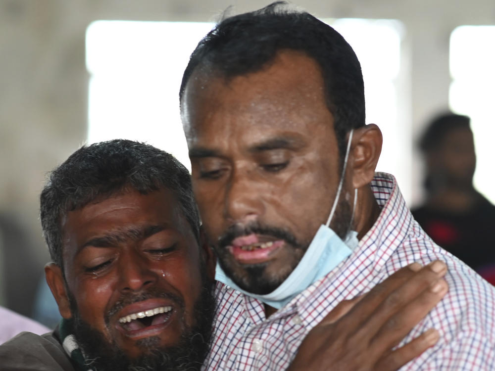 A person consoles his relative who is unable to find his five year old son travelling on a ferry which caught fire on the Sugandha River. Bangladesh fire services say at least 37 passengers have been killed.