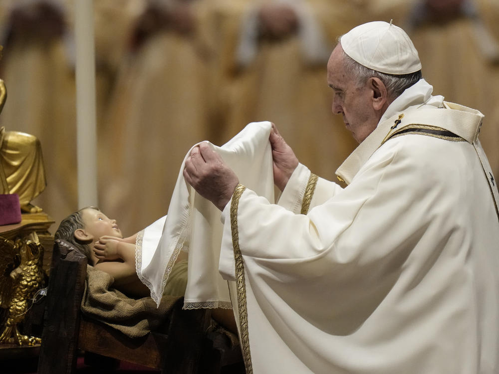 Pope Francis unveils a statue of Baby Jesus as he celebrates Christmas Eve Mass at St. Peter's Basilica, at the Vatican, on Friday.