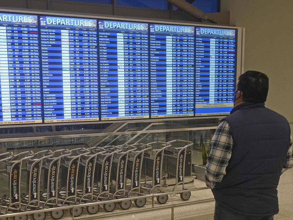 A man looks at the departures board at Salt Lake City International Airport on Friday. Hundreds more flights in the U.S. were canceled on Christmas Day — most involving Chinese airlines, as well as Delta and United in the U.S.