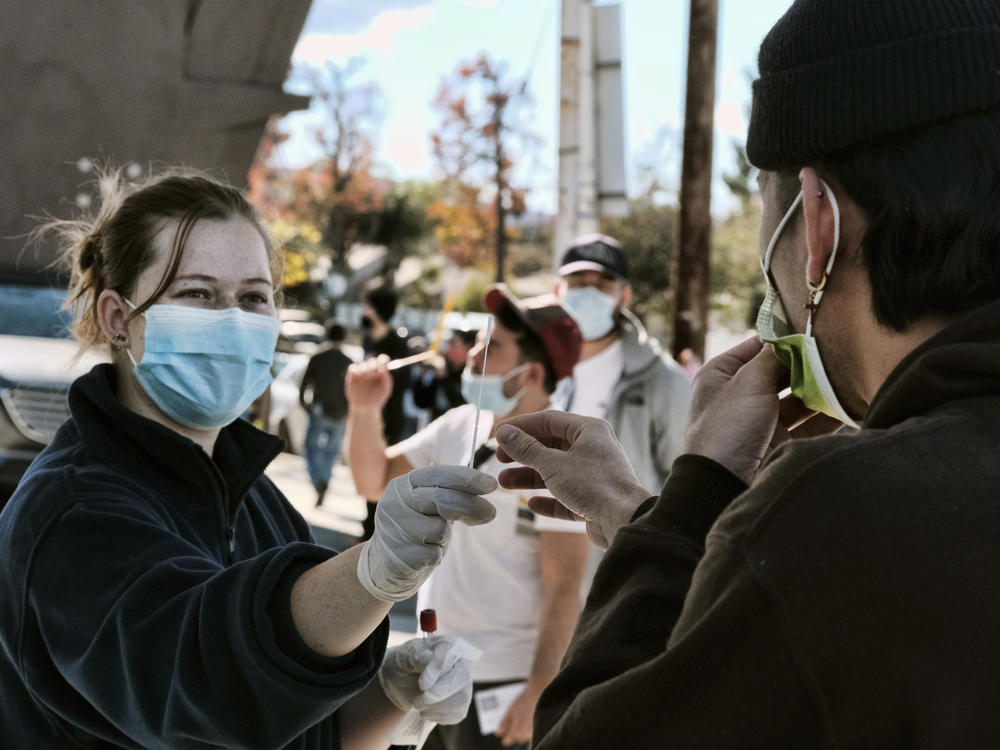 A man is handed a swab for a rapid test as people line up for coronavirus testing at a gas station in the Reseda section of Los Angeles on Sunday.