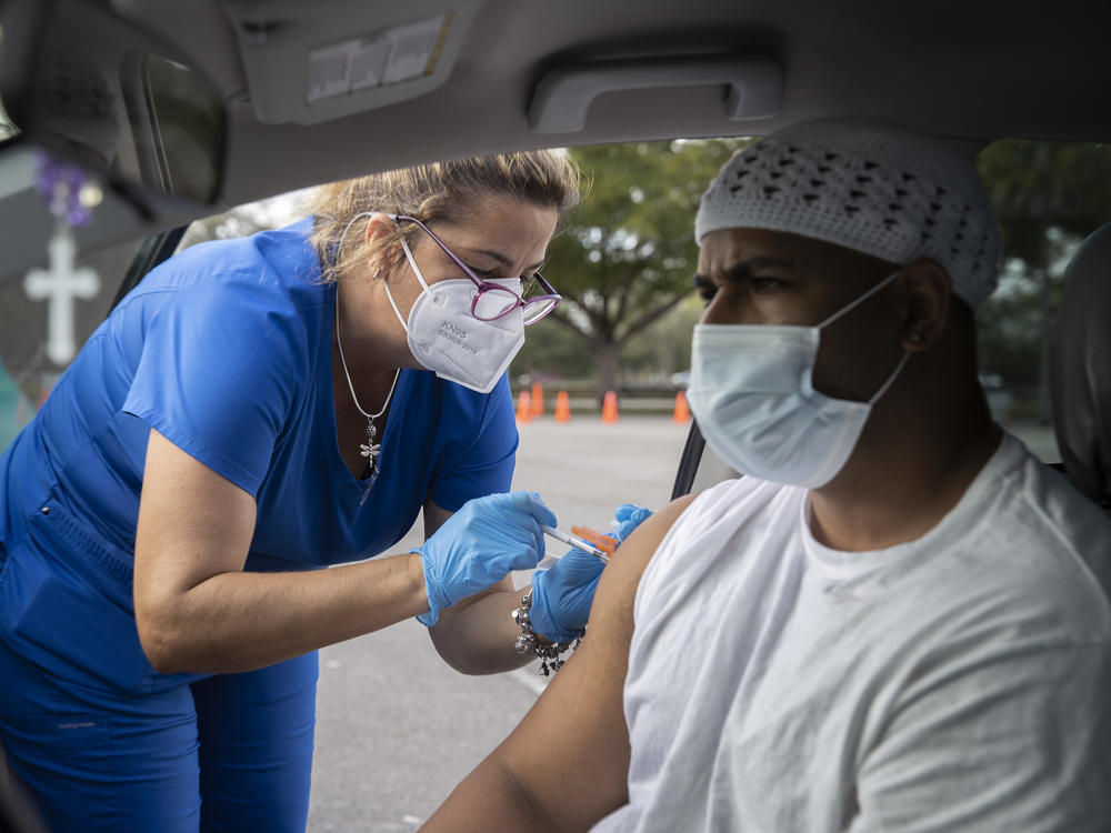 Alejandro Brown receives a COVID-19 vaccine from a health care worker at a drive-through site in Miami on Dec. 16.