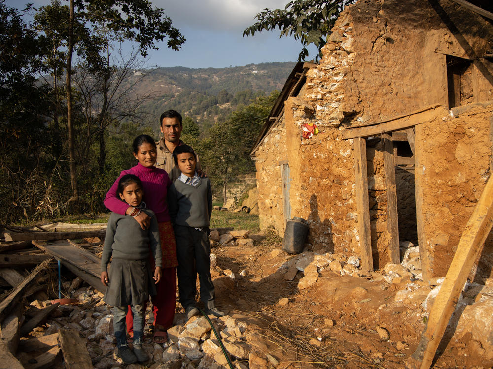 Prakash Balami, 29, was forced into an arranged marriage at 15. He poses with his wife, Sumeena, 27, and their children, Paratichya and Mukesh, next to their home, which was destroyed in the 2015 earthquake in Kagati village. 