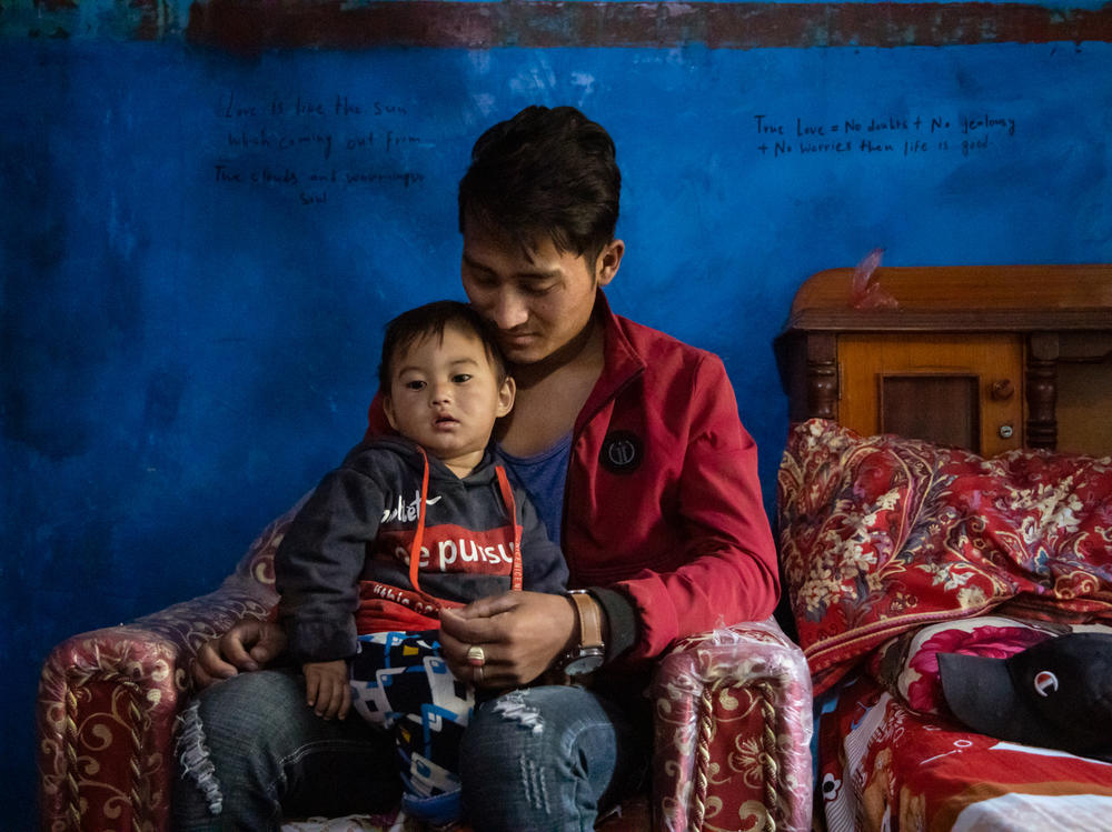 Nirazan Balami, 21, hold his 17-month-old son, Nir. He married at 17 under intense pressure from his wife's family.