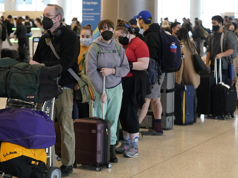 Travelers wait in the ticketing line at Salt Lake City International Airport on Monday. There have been thousands of flight delays and cancellations as the omicron variant spreads across the country. Unionized flight attendants are wary of new CDC guidelines that shorten the isolation period.