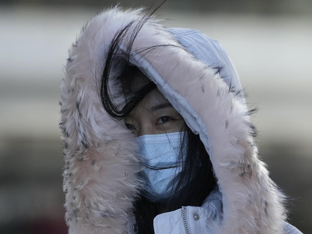 Women wearing masks to help curb the spread of the coronavirus walk against cold strong winds in Beijing, China, Thursday, Dec. 30, 2021.