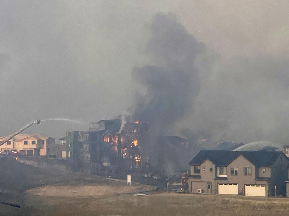 Firefighters spray water on a structure fire as a wildfire burns on Thursday in Superior, Colo.