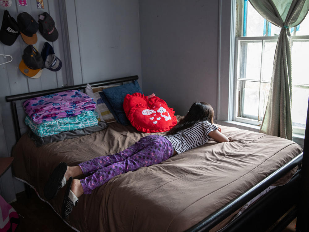 A 8-year-old looks out her bedroom window during self-quarantine with her family due to COVID-19.