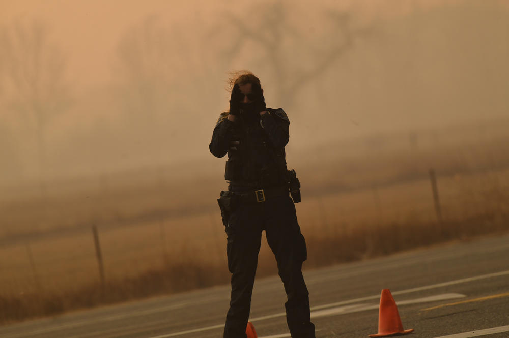 Dec. 30: Louisville, Colo. — A police officer holds her head at the corner of 96th Street and West Dillon Road in the strong wind.