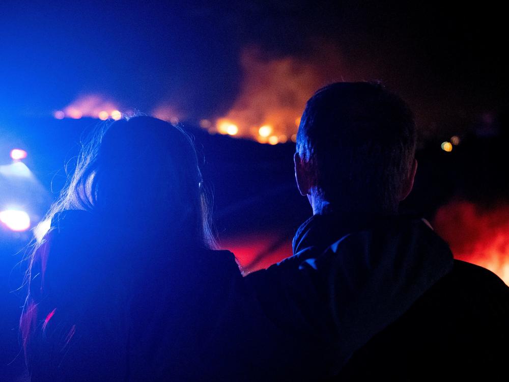 Dr. Bonnie Abbott (left) embraces her husband George as they watch flames engulf homes as the Marshall Fire spreads through a neighborhood in the town of Superior in Boulder County, Colorado on Thursday.