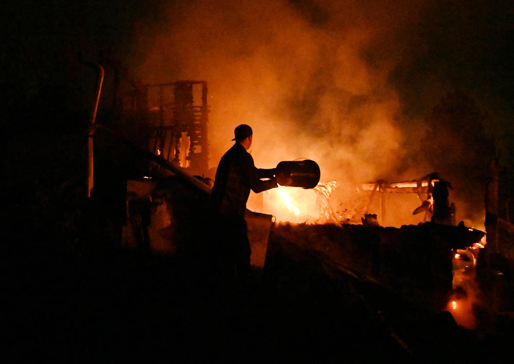 Dec. 31: Louisville, Colo. — A good Samaritan tosses buckets of water on a home that was burned in the Marshall Fire in Boulder County.