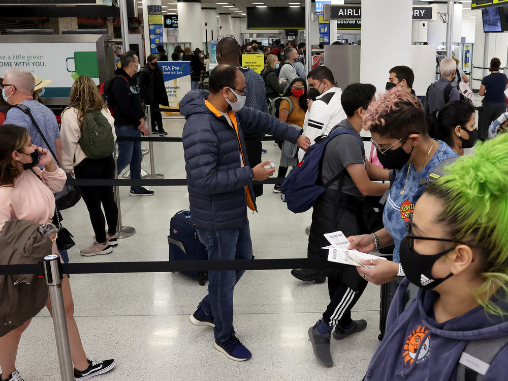 Travelers make their way through Miami International Airport on Tuesday. Airlines canceled more than 2,400 U.S. flights by midday on Saturday, according to the flight tracking website FlightAware.