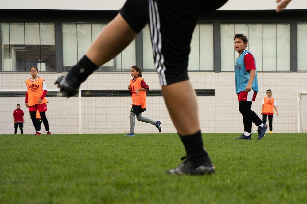 The coach kicks a soccer ball into play as the Afghan girls practice in Lisbon.