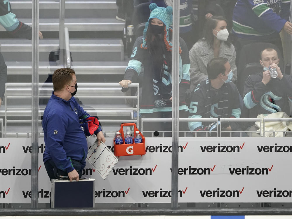Seattle Kraken fan Nadia Popovici (center) looks toward Vancouver Canucks assistant equipment manager Brian 