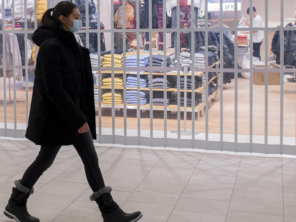 A woman walks by a closed store in a shopping mall in Montreal, Sunday as the COVID-19 pandemic continues in Canada. Some new measures put in place by the Quebec government, including the closure of stores, go into effect today.
