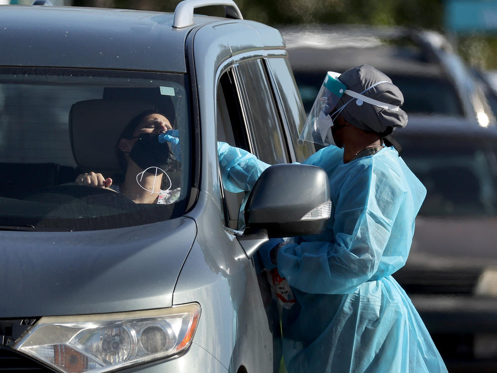 A health care worker conducts a test at a drive-through COVID-19 testing site at Zoo Miami last Wednesday in Miami. In response to the increasing demand for COVID-19 tests, Miami-Dade County opened two new testing sites and expanded hours at the Zoo Miami testing location.