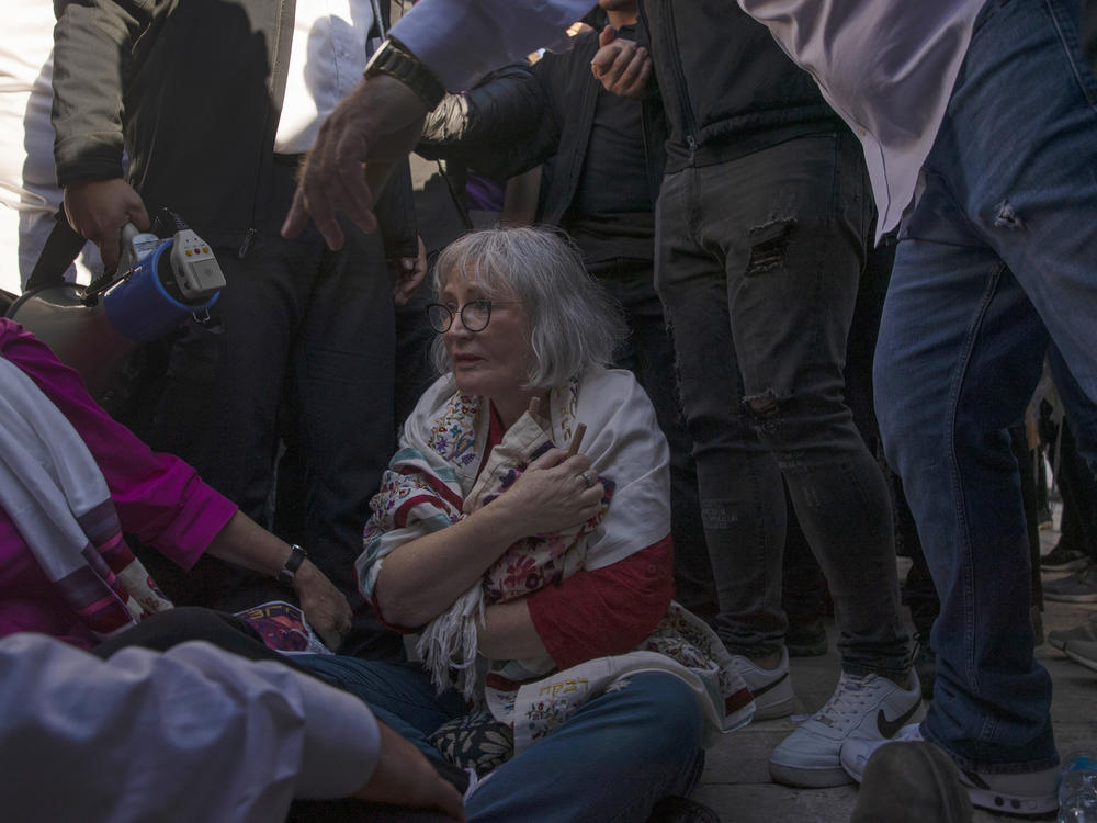 A member of the Women of the Wall clutches a Torah scroll, as she is surrounded by Israeli security forces holding back protesters at the Western Wall.