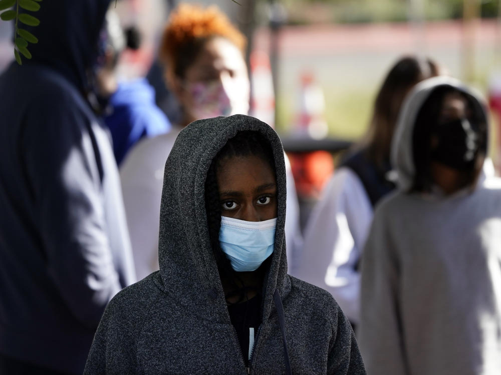 A young person wears a mask while waiting in line at a COVID-19 testing site on the Martin Luther King Jr. medical campus on Monday in Los Angeles.