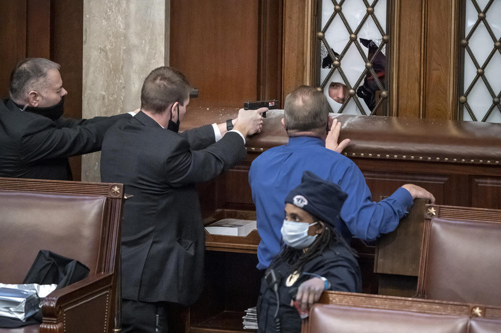 U.S. Capitol Police agents aim their guns as a pro-Trump mob tries to break into the House of Representatives chamber. Rep. Troy Nehls, R-Texas, in the blue shirt, talks to one of the rioters.