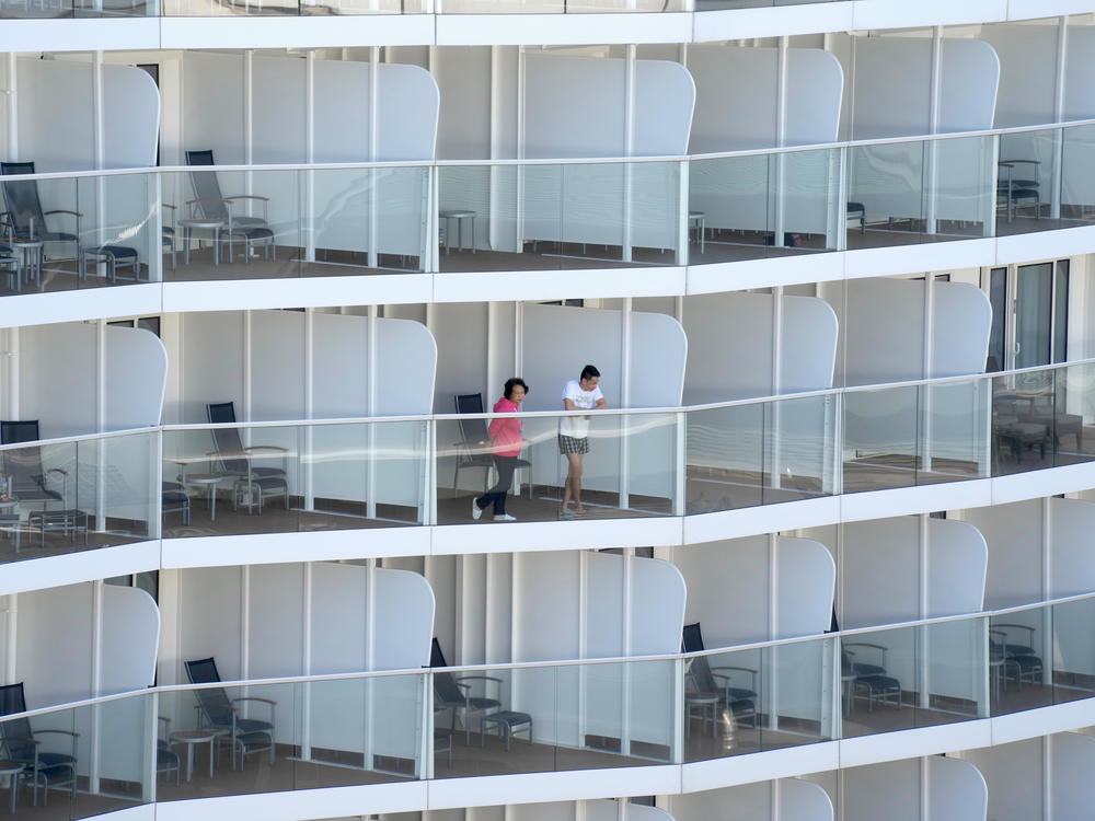 Passengers look out from the Spectrum of the Seas cruise ship docked in Hong Kong on Wednesday. Thousands of passengers were being held on the ship for coronavirus testing after health authorities said nine passengers were linked to a recent omicron cluster and ordered the ship to turn back.