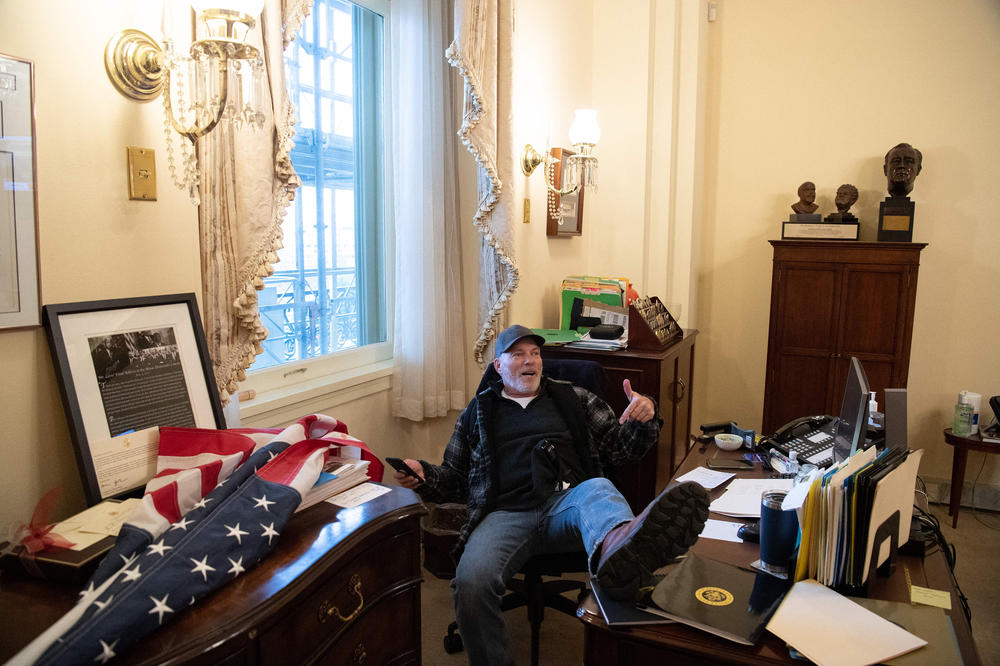 Richard Barnett, a supporter of President Donald Trump, sits inside the office of Speaker of the House Nancy Pelosi after breaking into the Capitol.